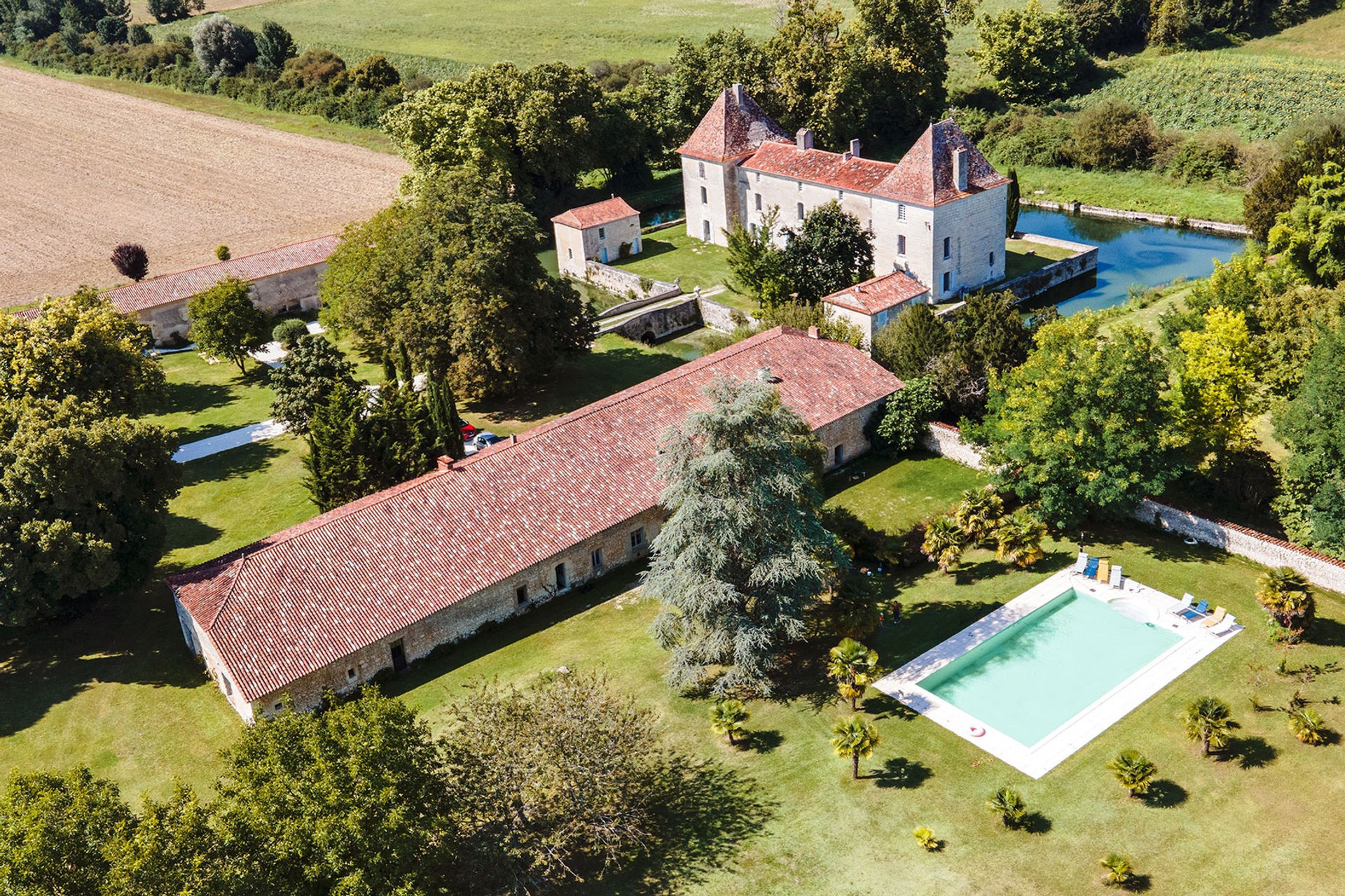 Aerial view of Château de la Mothe, its moat, outbuildings and swimming pool