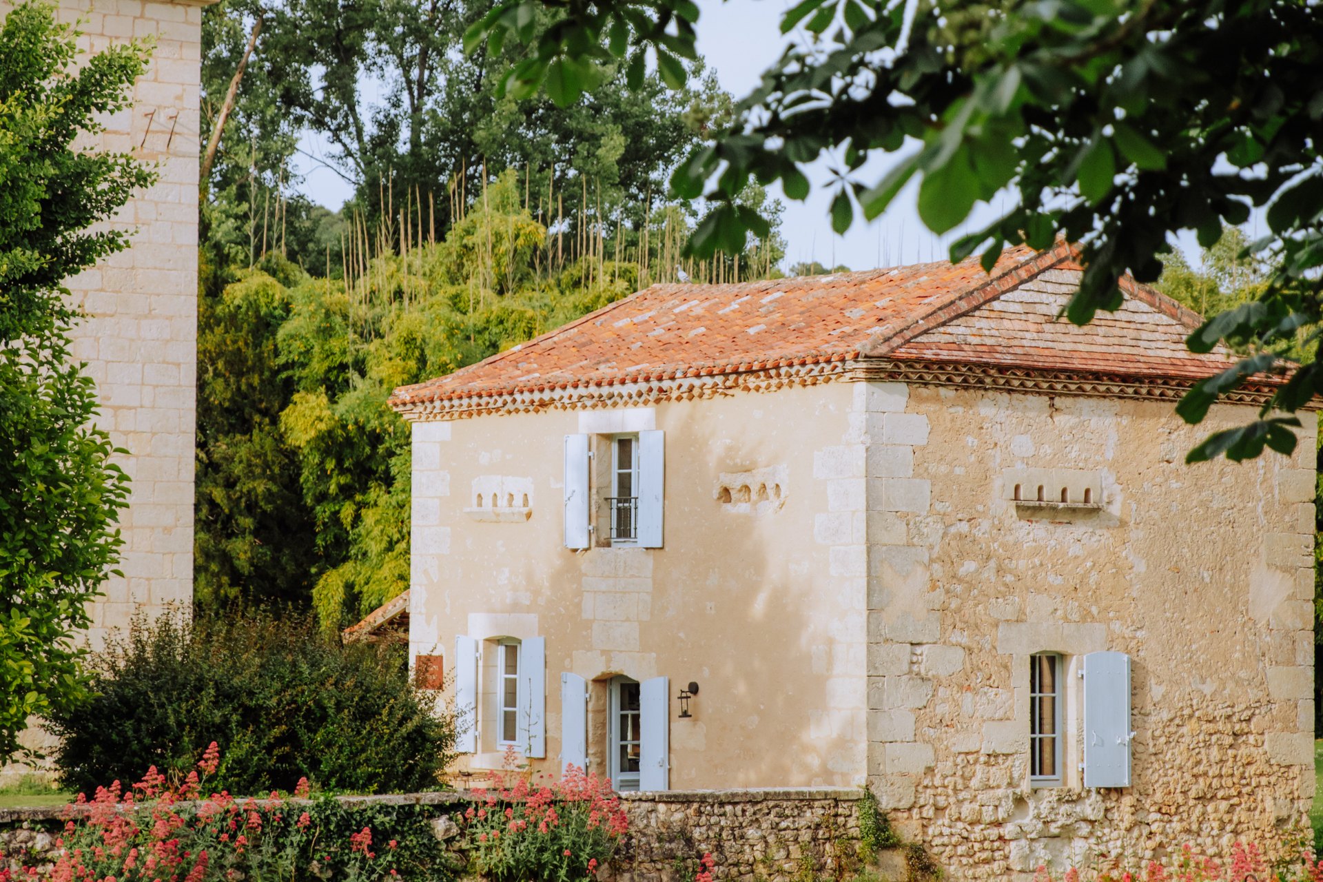 One of the estate's stone gîtes with pale shutters and flowers in the garden