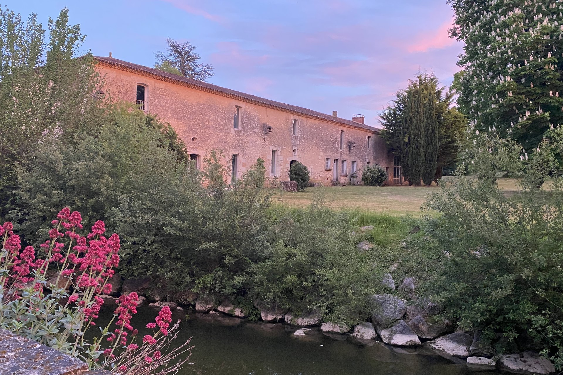 The estate at dusk, pink sky above the moat and gardens