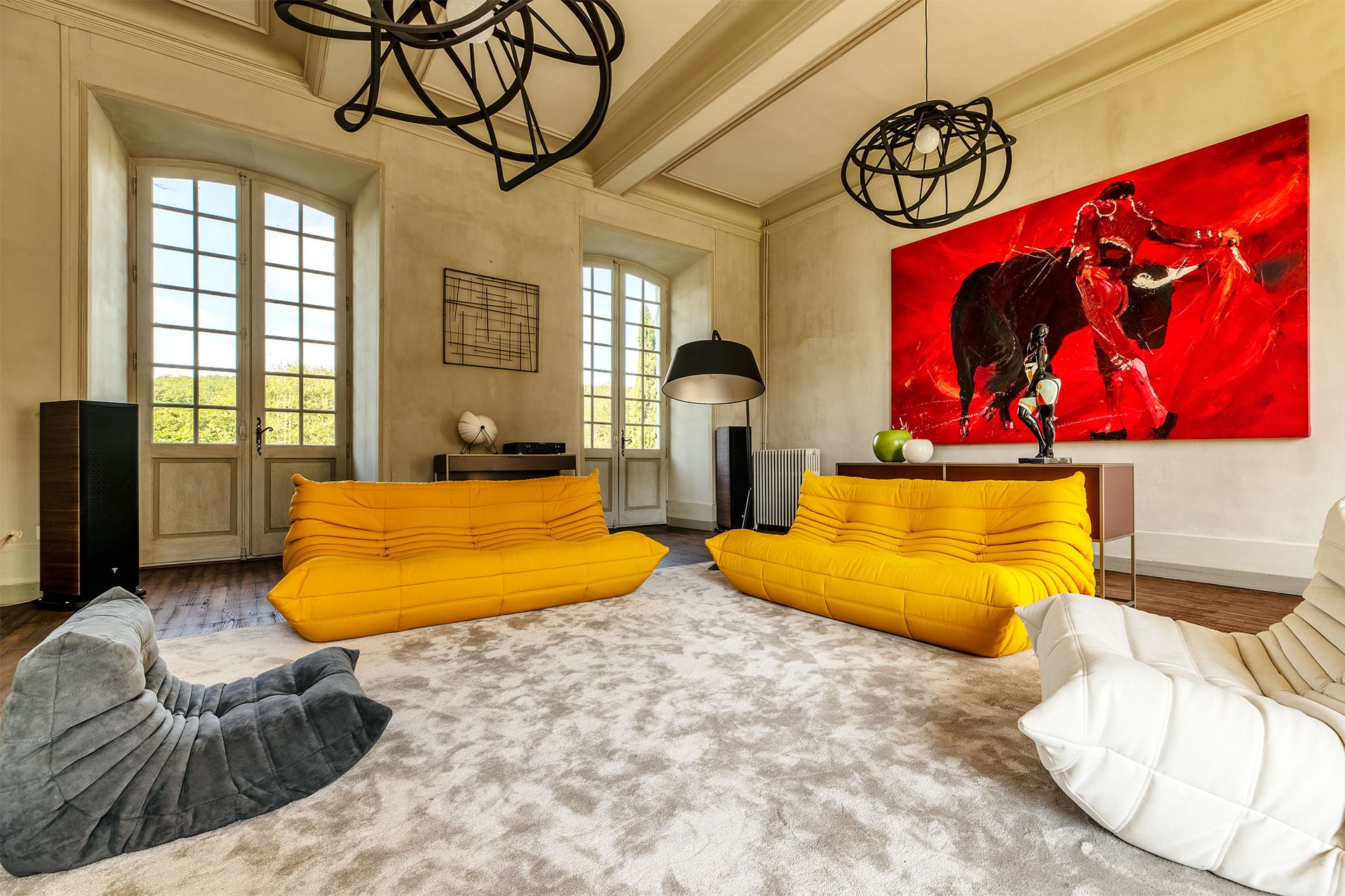 A château salon with yellow lounge sofas and tall shuttered windows